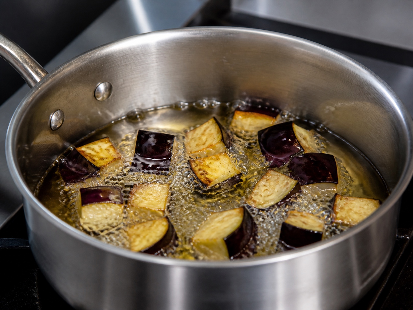 Небольшая партия баклажанов свободно жарится в сотейнике
